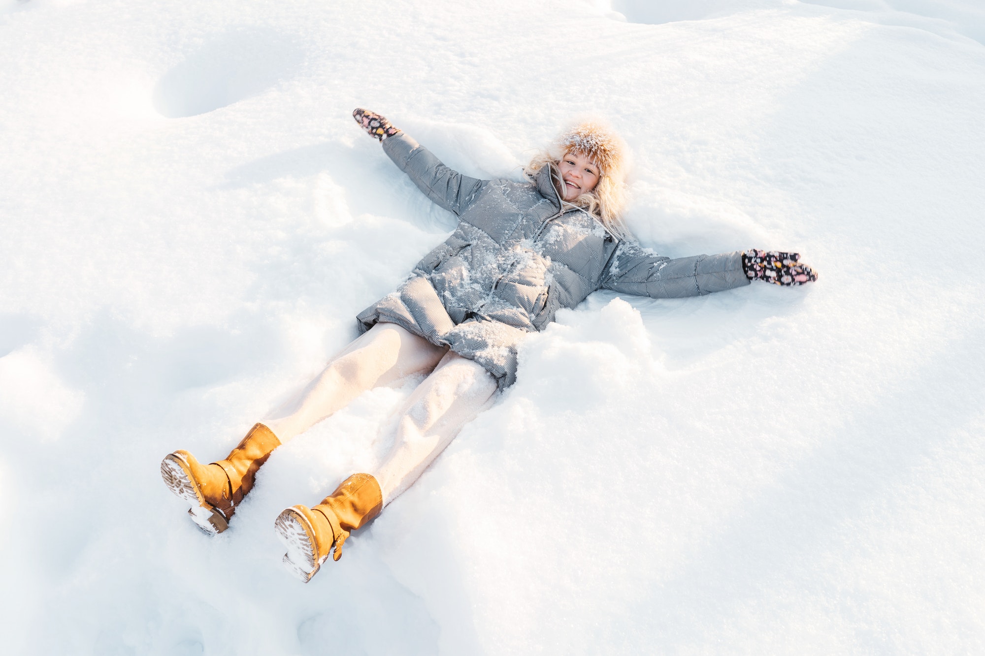 Woman lying in snow making snow angel.